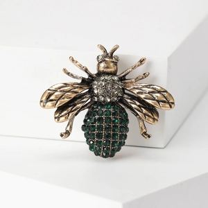 Macro detail of vintage bee brooch with sparkling crystals on antique gold finish