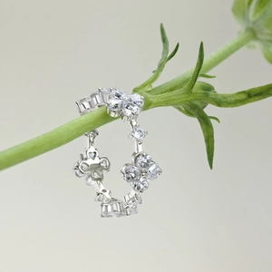 Macro shot of silver floral ring with white zircons on a natural green plant stem