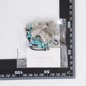 Close-up of bohemian silver cross necklace and turquoise bead set in retail packaging