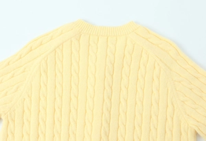 Detailed back view of yellow knit sweater showing intricate cable stitch texture