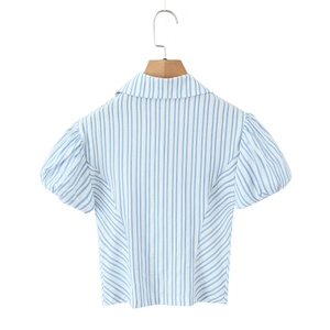 Dettaglio della camicia a righe bianche e blu con maniche a sbuffo e trama del tessuto fine