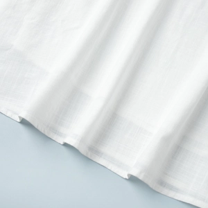 Detail shot of white cotton-linen fabric with textured weave and neat stitching