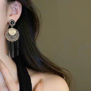 Détail de boucles d'oreilles vintage à pompons dorés et noirs sur un mannequin