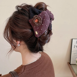 Detail of burgundy plush flower hair claw clip with polka dots on a woman's hairstyle