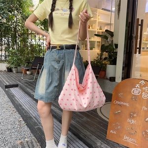 Detailed shot of pink heart canvas tote bag held by model in casual outdoor setting