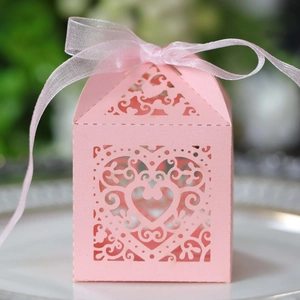 Macro shot of pink heart laser-cut candy box with silk ribbon for wedding favors