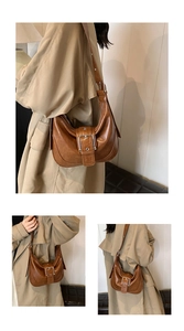 Close-up of brown crescent underarm bag with large silver buckle on stylish khaki trench coat