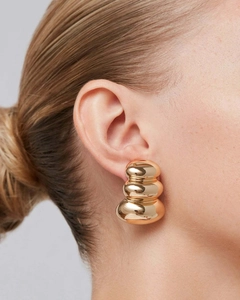 Gros plan de boucles d'oreilles boules triples plaquées or 18 carats sur un modèle