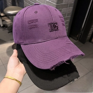 Close-up of distressed cotton baseball caps with DG embroidery and vintage frayed details