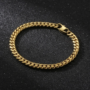 Detailed close-up of a gold-plated Cuban link chain bracelet on a dark textured surface