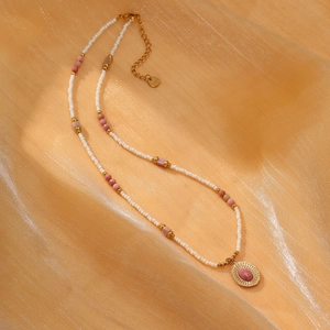 Detailed view of handmade beaded necklace with pink stone pendant on silk fabric