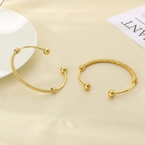 Detail of 18K gold plated stainless steel bangles with mesh texture and round ball ends