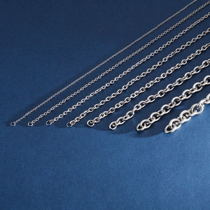 Various sizes of silver stainless steel O-link chains for men on a blue background