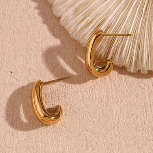Macro detail of glossy 18K gold plated double layer U-shaped earrings on stone