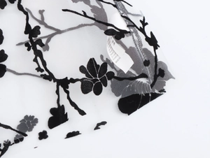 Detail of the white mesh blouse with black floral pattern and clothing care label