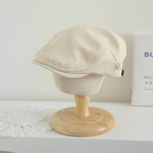 Détail d'un béret beige avec bouton latéral sur un mannequin en bois élégant