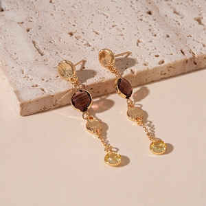 Detail of gold tassel earrings featuring purple and yellow crystals on a stone base