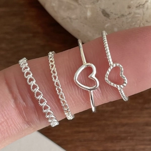 Close-up of diverse S925 sterling silver heart-shaped rings worn on fingers
