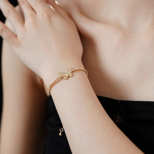 Détail d'un bracelet papillon doré ajustable avec oxydes de zirconium sur le poignet