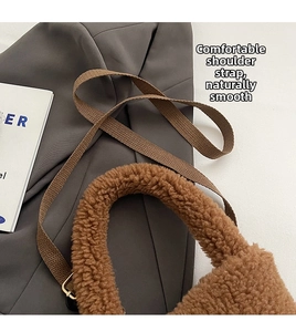 Detail of brown plush bucket bag with wide woven strap on a soft fabric background