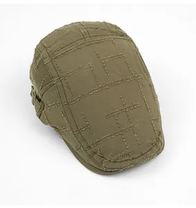 Detail view of military green cotton newsboy cap featuring distressed check textures