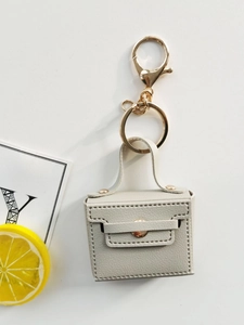 Creative beige leather mini bag keychain with gold hardware on a bright white background