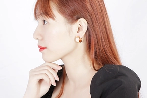 Detail of elegant gold hoop earrings with white inlay worn by a model in studio lighting