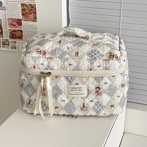 Quilted cream makeup bag with cartoon bear patterns and decorative ribbon zipper