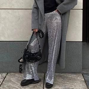 Street style view of women silver sequin wide leg trousers paired with a grey coat