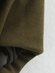 Detailed macro view of olive green cotton fabric texture and seamless garment stitching