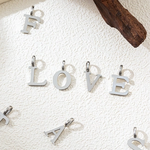 Macro detail of silver stainless steel alphabet pendants with a brushed metal texture