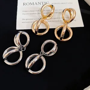 Orecchini a cerchio geometrici intrecciati in oro e argento su carta elegante