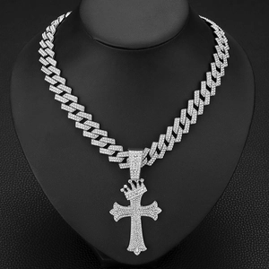 Détail d'un pendentif croix couronne argenté serti de cristaux sur une chaîne cubique