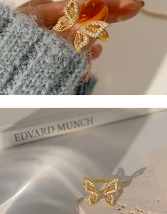 Detail showing a golden butterfly open ring with zircon stones on a book