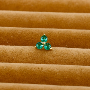 Macro shot of three green cubic zirconia stones set in golden stainless steel cartilage stud