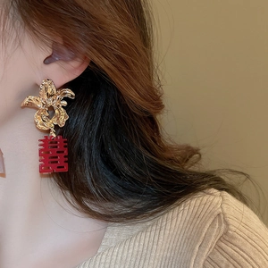 Detail of bridal floral earrings with golden flowers and red double happiness pendants