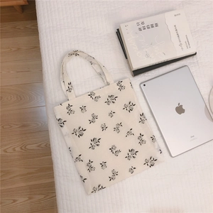 Detail view of cream canvas tote bag with black floral rose prints and dual handles
