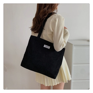 Fashionable black corduroy tote bag worn by model, showcasing large capacity and soft texture