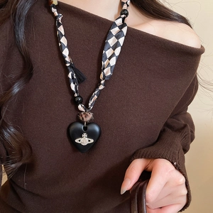 Detail of beaded heart pendant necklace with checkered silk ribbon and rhinestone planet logo