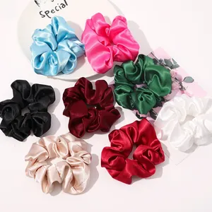 Flat lay of large silk satin scrunchies in eight colors displayed on white plate