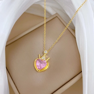 Detail of pink heart pendant with crown and diamonds on golden chain in jewelry box