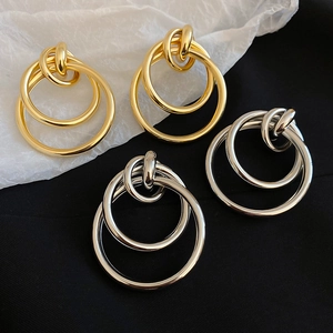 Détail de boucles d'oreilles multicercles dorées et argentées sur un fond texturé élégant