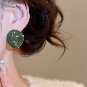 Detailed view of model wearing a dark green enamel earring with 14k gold plated edges
