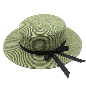 Gros plan sur un chapeau de paille vert foncé avec ruban gros-grain noir et noeud