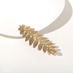 Macro detail of gold leaf hair clip showing intricate vein texture on a white background