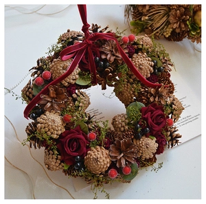 Detail of vintage Christmas wreath with pine cones, silk roses, and red velvet bow