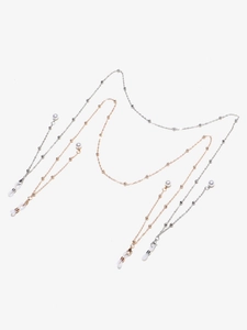 Detailed macro view of gold and silver eyeglass chains with pearl beads and lobster clasps