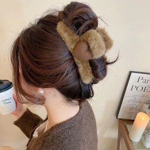 Close-up of a brown plush heart hair claw clip styled on a model in a cozy winter setting