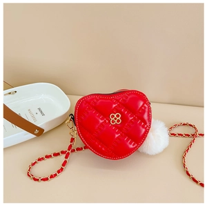 Detail of red heart-shaped quilted leather crossbody bag with golden flower buckle and fur ball