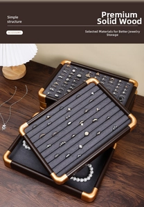 Detail of walnut wood jewelry tray with gold metal corners and grey velvet ring slots